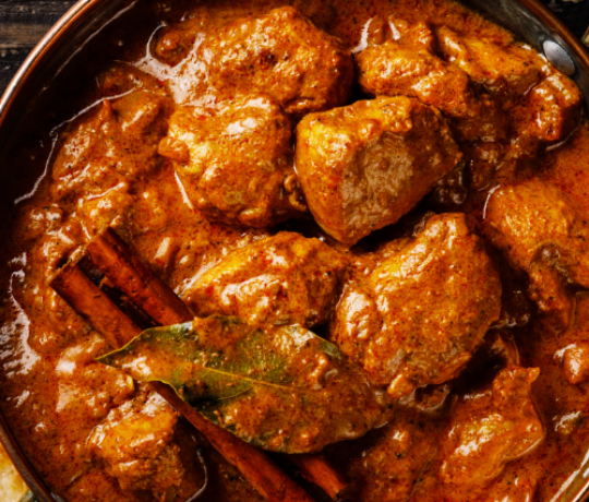 Bowl filled with curry, garnished with cinnamon sticks